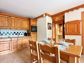 Een houten keuken met betegelde achterwand, houten kastjes en een eettafel gedekt voor vier personen.
