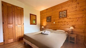 Une chambre à coucher aux murs lambrissés, avec un lit, des tables de chevet et une porte.