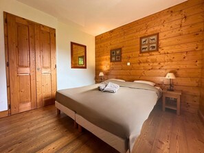 Een slaapkamer met houten lambrisering, een bed, nachtkastjes en een deur.