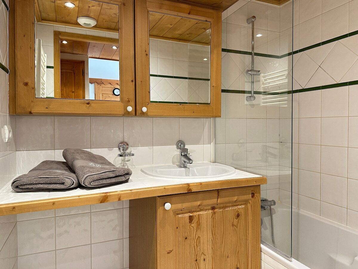 A bathroom with a wooden vanity, a sink, and a glass shower enclosure.