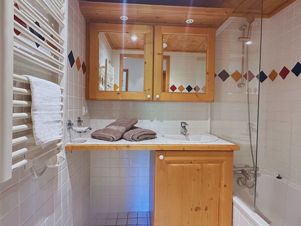 A bathroom with a wooden vanity, a sink, a mirror, and a shower.