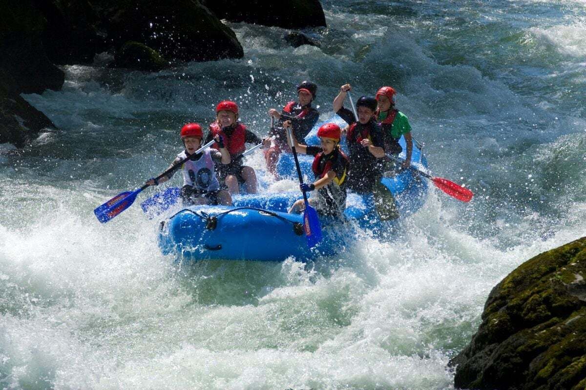 A group of people in a blue raft navigating through rough waters.