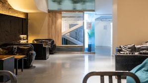 Eine moderne Lobby mit Ledersitzgelegenheiten, einer Treppe und einer Glaswand mit Pflanzen.