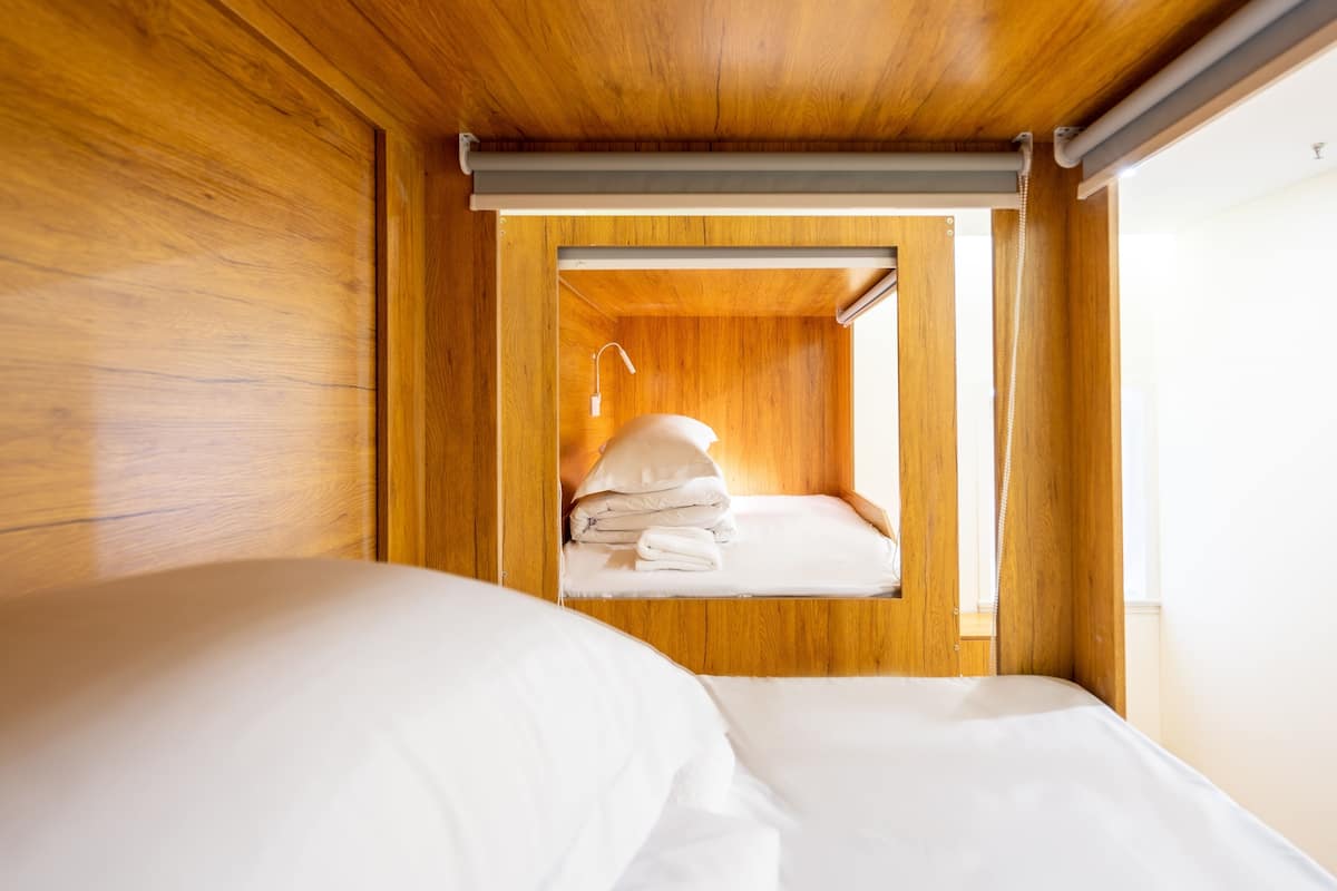 A wooden room with two beds, one in the foreground and one in the background.