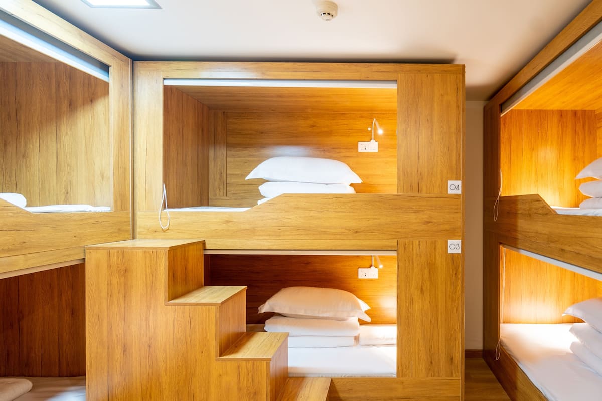 A bunk bed room with wooden walls and a staircase leading to the upper bunk.