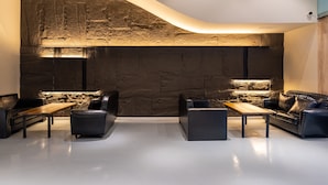 Ein modernes Wohnzimmer mit einer Wand aus Stein, Ledersofas und einem Holztisch.