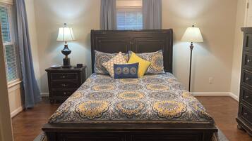 A bedroom with a large bed, two bedside tables, a dresser, and a nightstand.