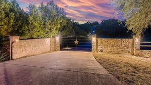 A gated driveway leading to a property with a stone wall and a star-shaped sign. - Gated Hill Country Escape: 1 Gb Internet & Seclusion (Spicewood)