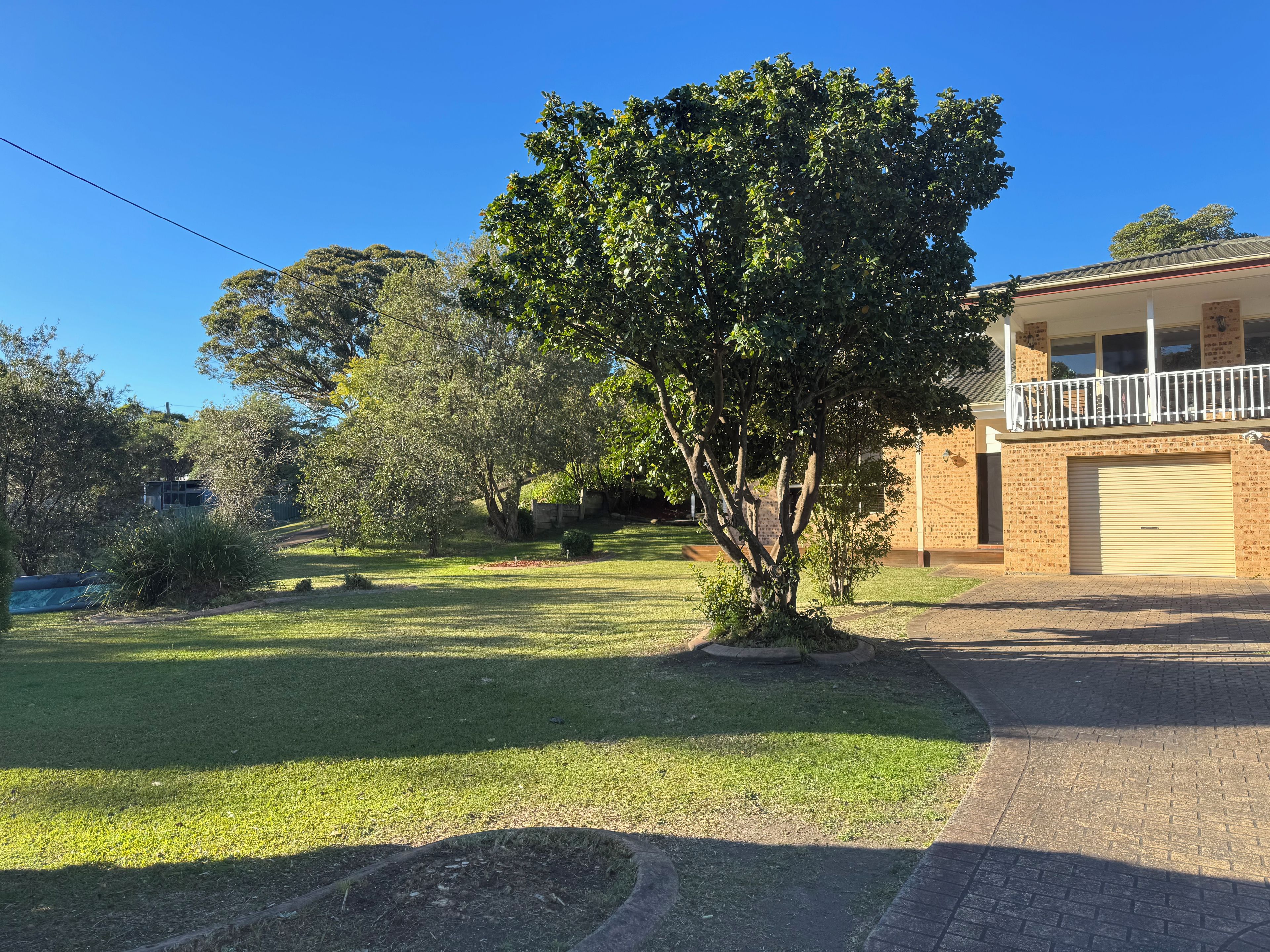 A residential property with a well-maintained lawn, a tree, and a two-story building with a garage.