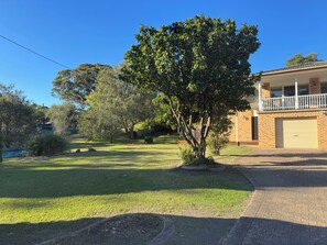 A residential property with a well-maintained lawn, a tree, and a two-story building with a garage.