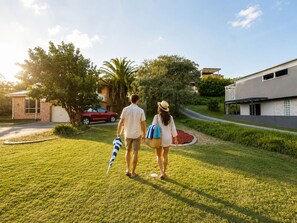 Un couple se promène sur une pelouse bien entretenue, avec une maison moderne en arrière-plan.