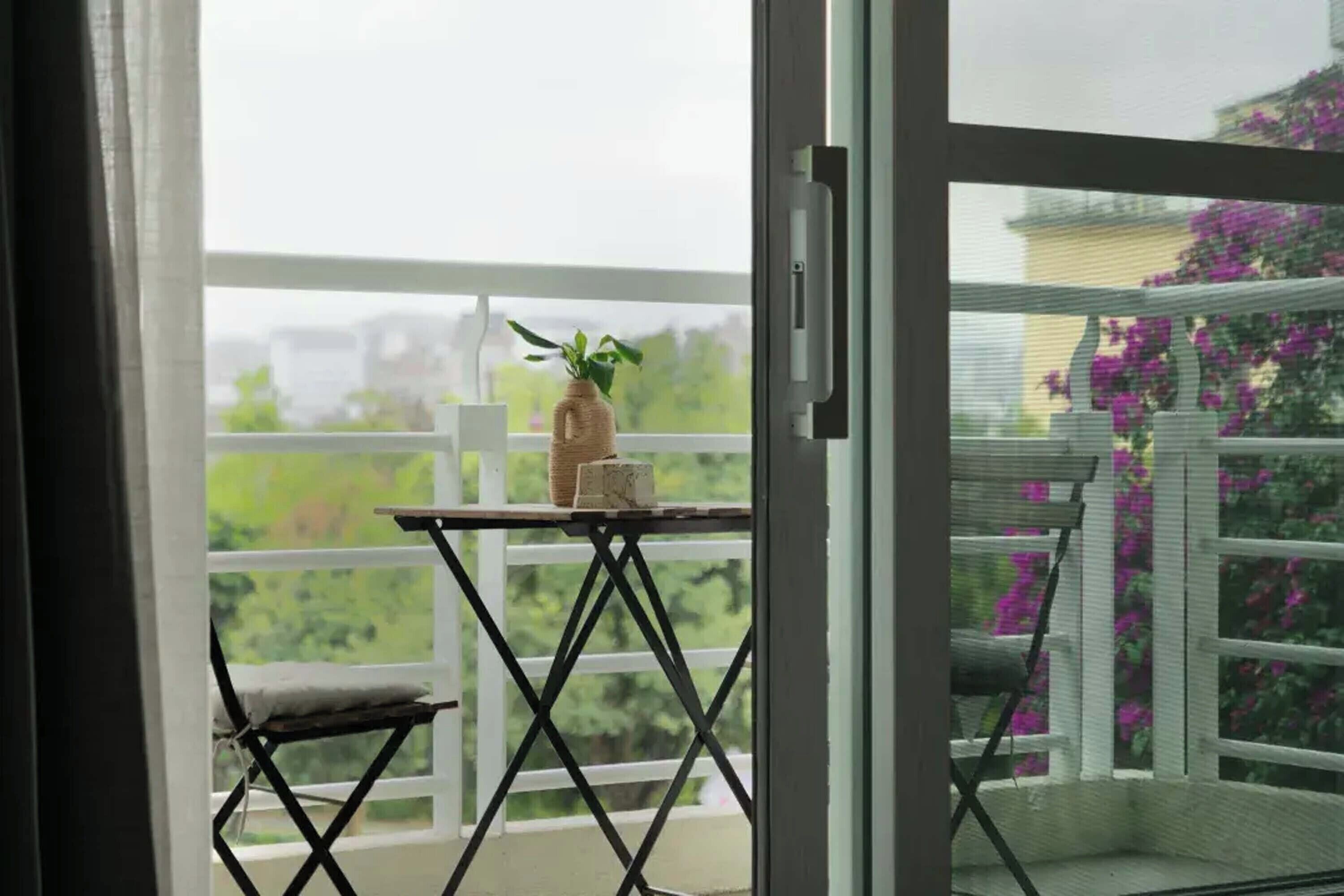 A balcony with a small table, a chair, and a potted plant.