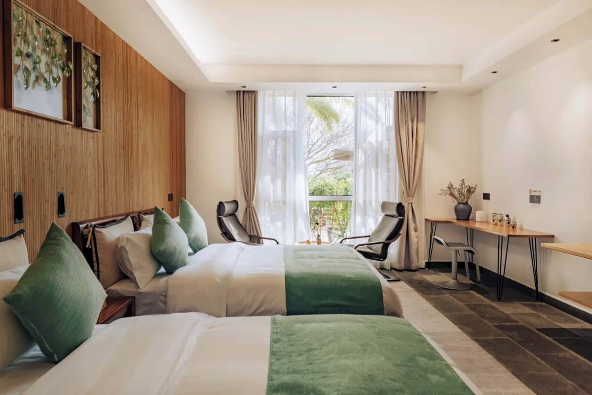 A hotel room with two beds, a desk, and a chair.