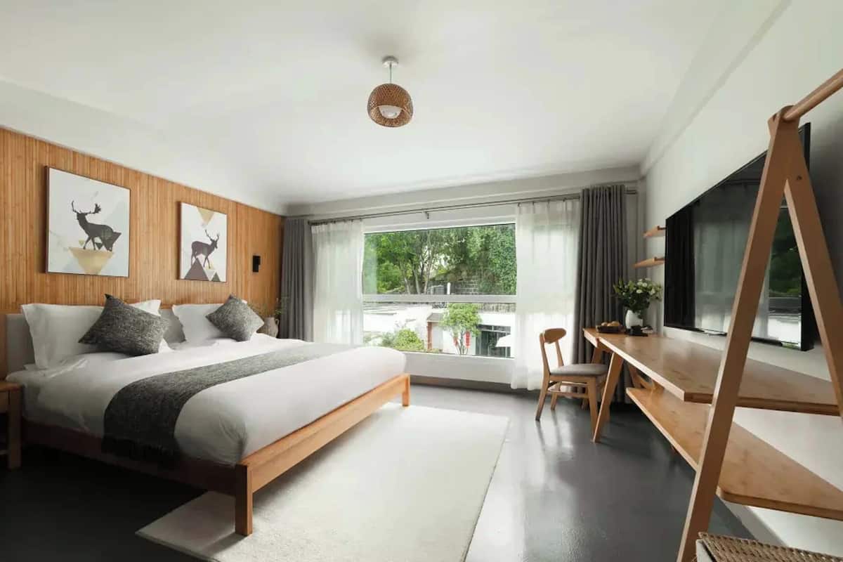 A modern bedroom with a large bed, a desk, and a TV.