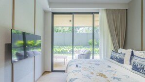 Una camera da letto con un letto, una televisione, un balcone con una sedia e vista sul verde.