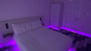 A bedroom with a bed, a wardrobe, and a nightstand. - Spacious 1-Bed Apartment - Sleeps 2 & Parking (Truro)