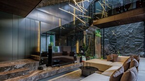 Een modern interieur met een stenen muur, een bank, een televisie en een trap.