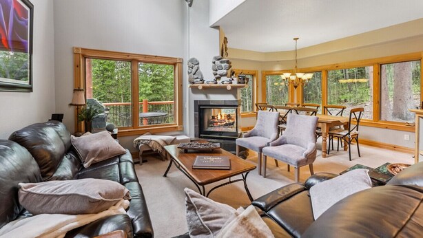 A spacious living room with a fireplace, leather sofas, and a dining area with wooden furniture. - Ski-In Ski out on Skyway • Hot Tub • 4BR • Walk to Town (Breckenridge)