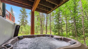 A hot tub in a forested area with a wooden deck and a view of trees. - Ski-In Ski out on Skyway • Hot Tub • 4BR • Walk to Town (Breckenridge)