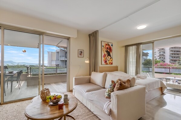 A modern living room with a sofa, a coffee table with fruit, and a painting.