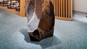 A modern interior with a unique ceiling design, a central rock sculpture, and a wooden slat wall. - KIORI Hotel Higashino Toin (Kyoto)