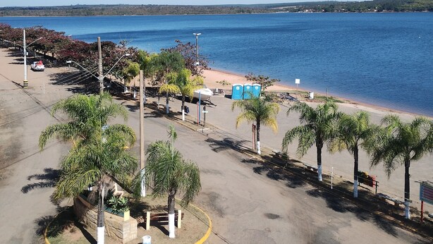 A beachside parking area with palm trees, a boat, and a clear view of the sea. - Kitchenette flat at the Broa dam with incredible views (Balneário Santo Antônio Itirapina)