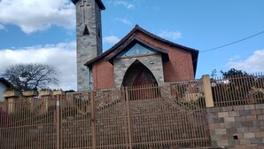 A church with a tall tower and a pointed arch entrance, surrounded by a wooden fence and a paved area in front. - Kitchenette flat at the Broa dam with incredible views (Balneário Santo Antônio Itirapina)