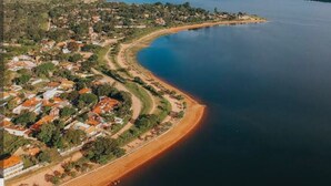 An aerial view of a coastal town with a curved shoreline, residential areas, and a large body of water. - Kitchenette flat at the Broa dam with incredible views (Balneário Santo Antônio Itirapina)