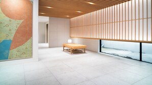A modern interior with a wooden slatted ceiling, a bench, and a large abstract wall art piece. - KIORI Collection Shinmachi (Kyoto)