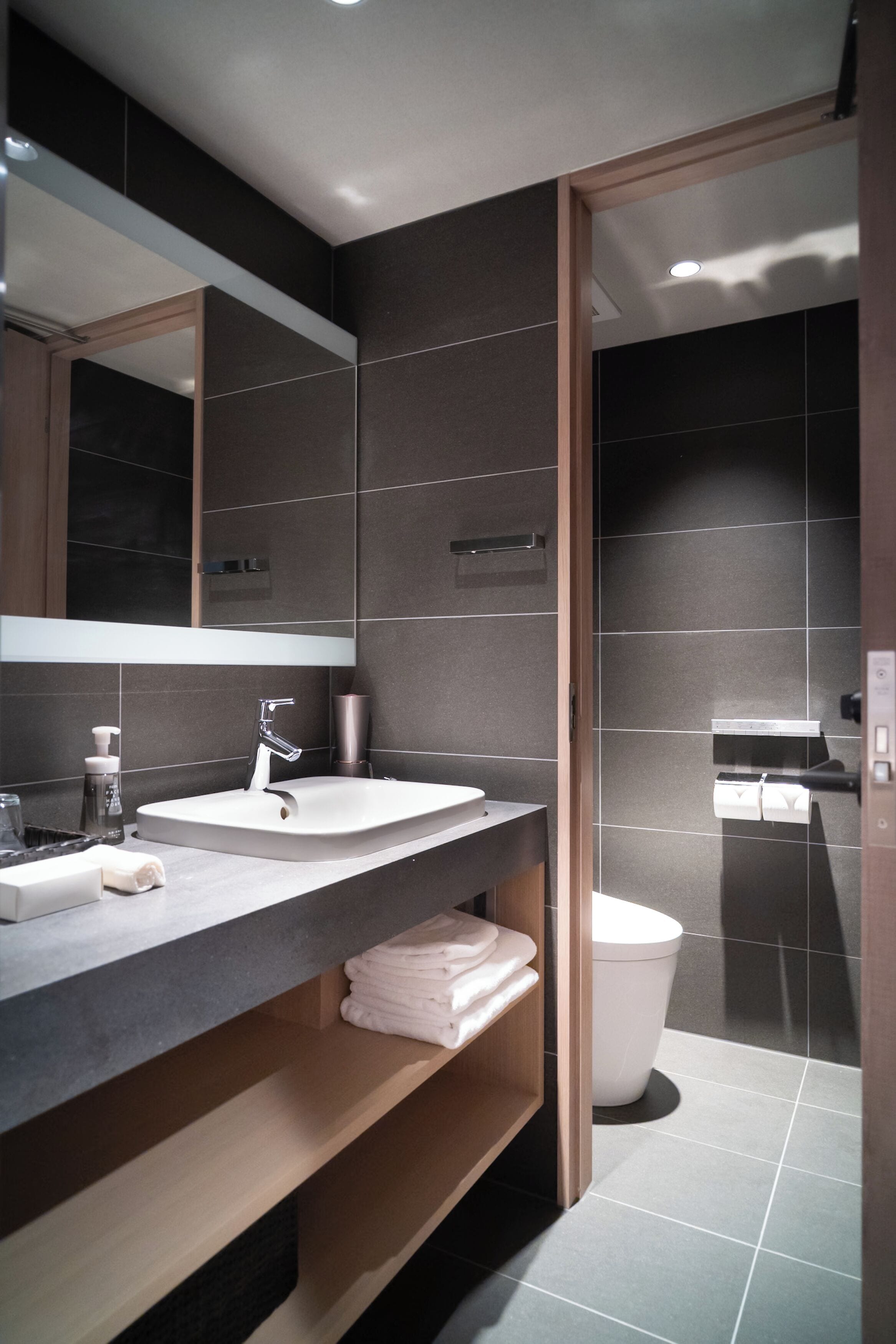 A modern bathroom with a large mirror, a sink, and a toilet.