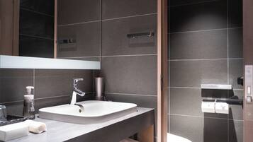 A modern bathroom with a large mirror, a sink, and a toilet.