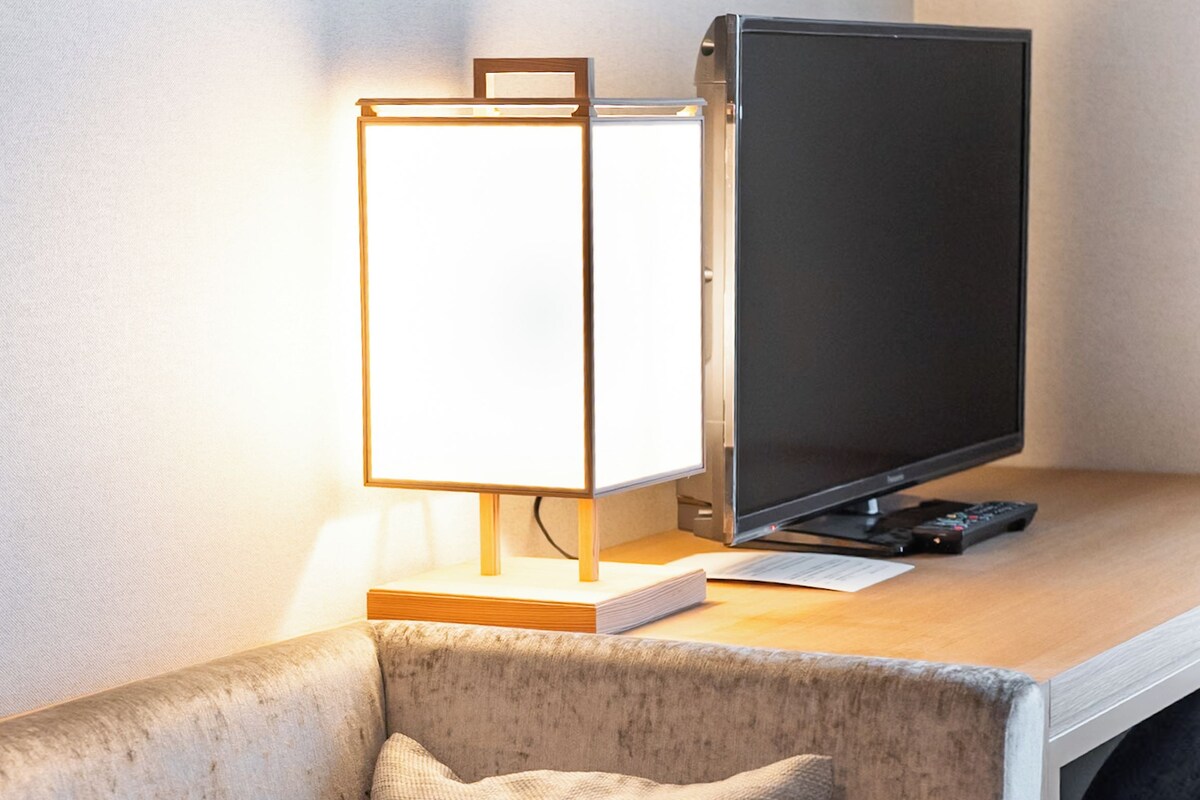 A modern living room with a sofa, a flat-screen TV, and a lamp.