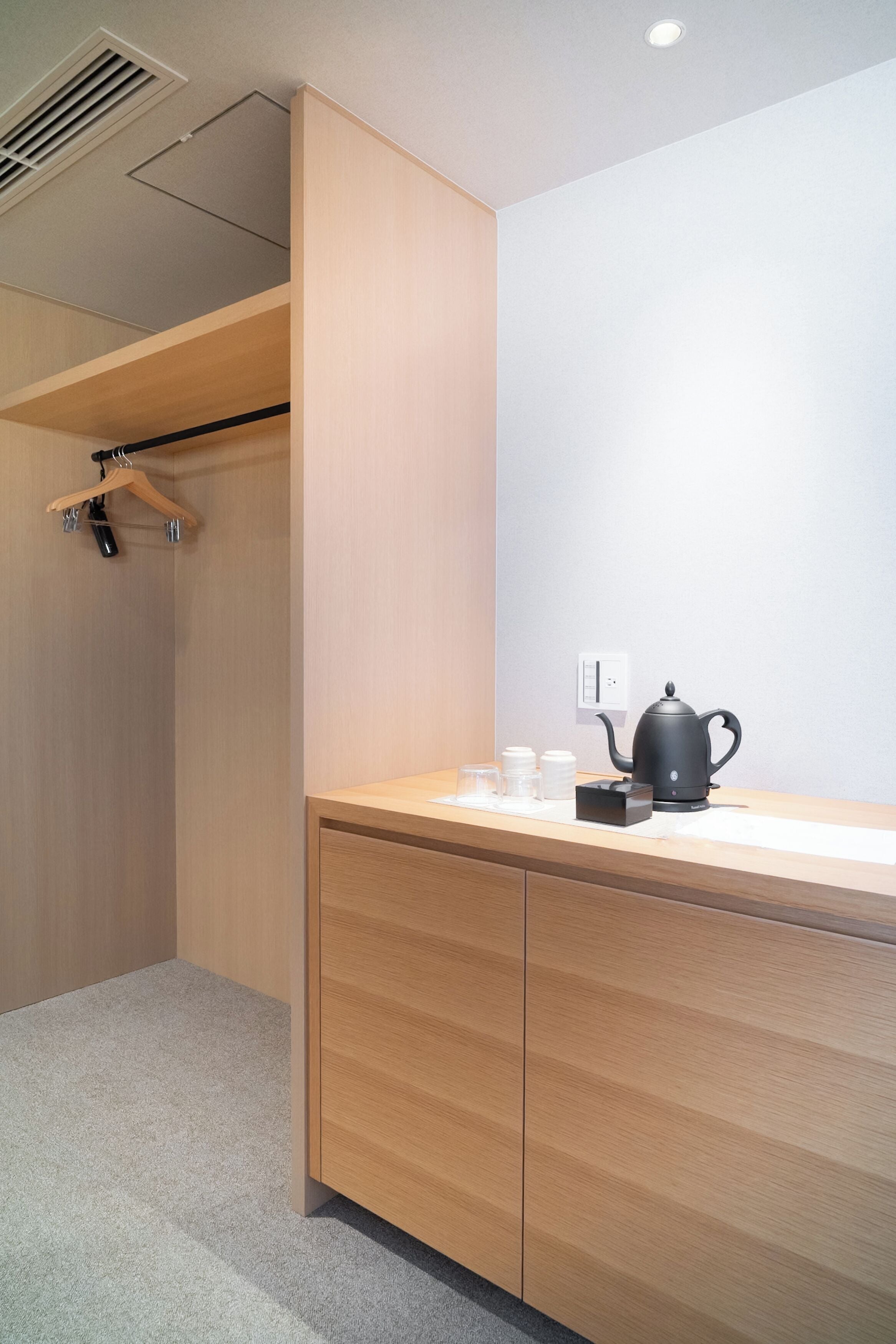 Une chambre moderne avec un bureau en bois, une bouilloire et une tasse.