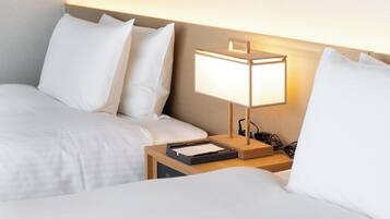 Een hotelkamer met twee bedden, een nachtkastje met een lamp en een kunstwerk aan de muur.