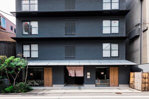 A modern multi-story building with a flat facade, large windows, and a covered entrance area. - KIORI Hotel Takakura (Kyoto)