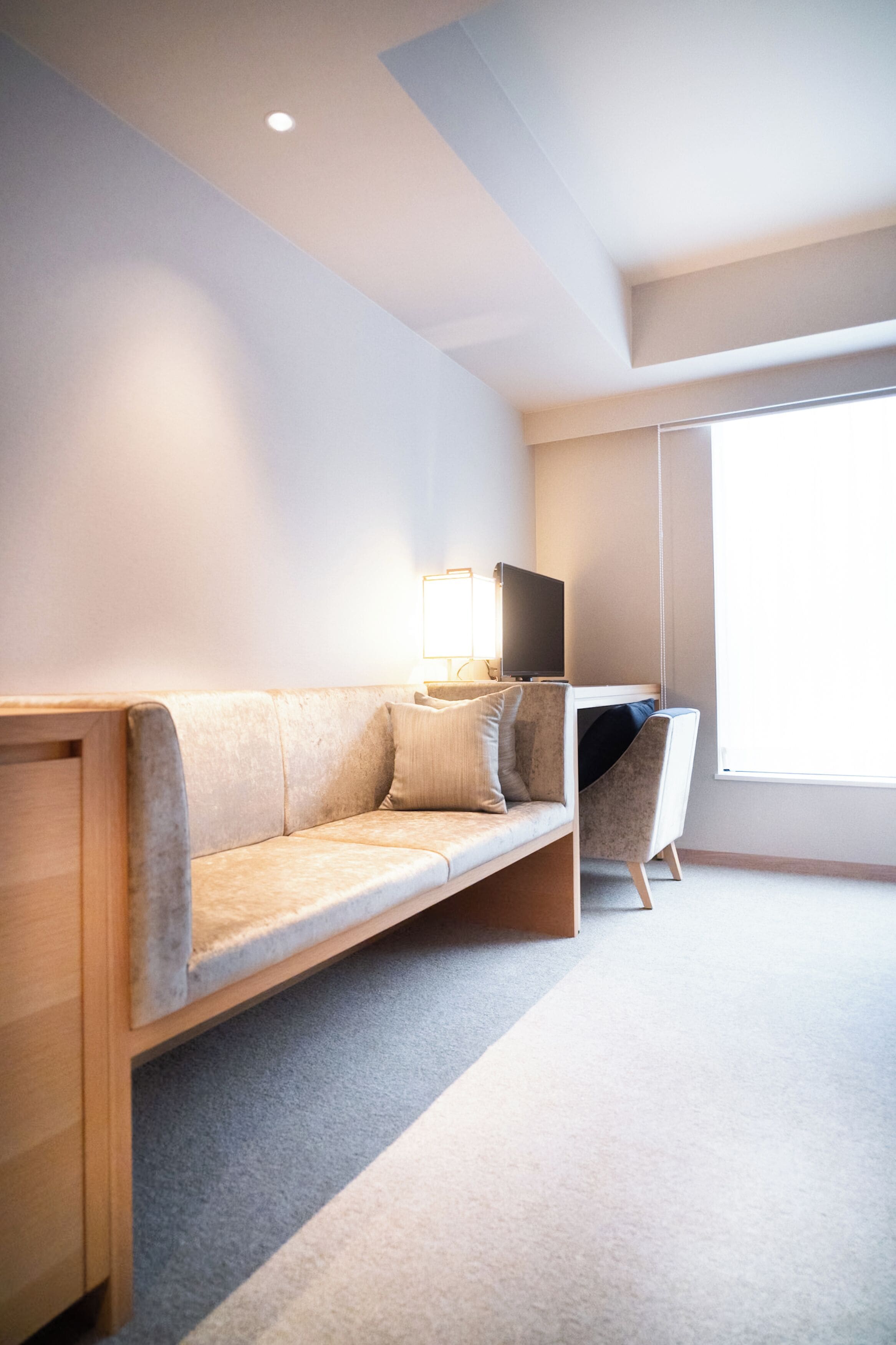 Une pièce moderne et minimaliste, comprenant un canapé, un bureau et un téléviseur.