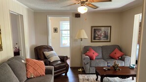 A living room with a brown leather armchair, a gray sofa, and a wooden coffee table.