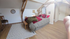 A bedroom with a bed, a wooden bench, a mirror, and a door. - Master bedroom 50 m2 Great comfort 5 minutes from Lac de Neufond (Vergt)