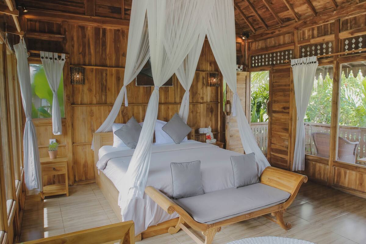 A wooden room with a bed, a sofa, and a nightstand.