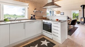 Une cuisine moderne avec des armoires blanches, un four encastré et une grande fenêtre donnant sur l’extérieur.