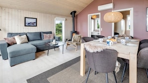 Un salon chaleureux avec un canapé, une table à manger dressée pour quatre personnes et une cheminée.