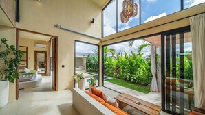 Uma sala de estar moderna com uma grande porta de vidro deslizante que dá para um jardim exuberante.
