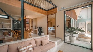 Um interior moderno com um sofá, uma mesa de centro e uma área de jantar com cadeiras e uma mesa.