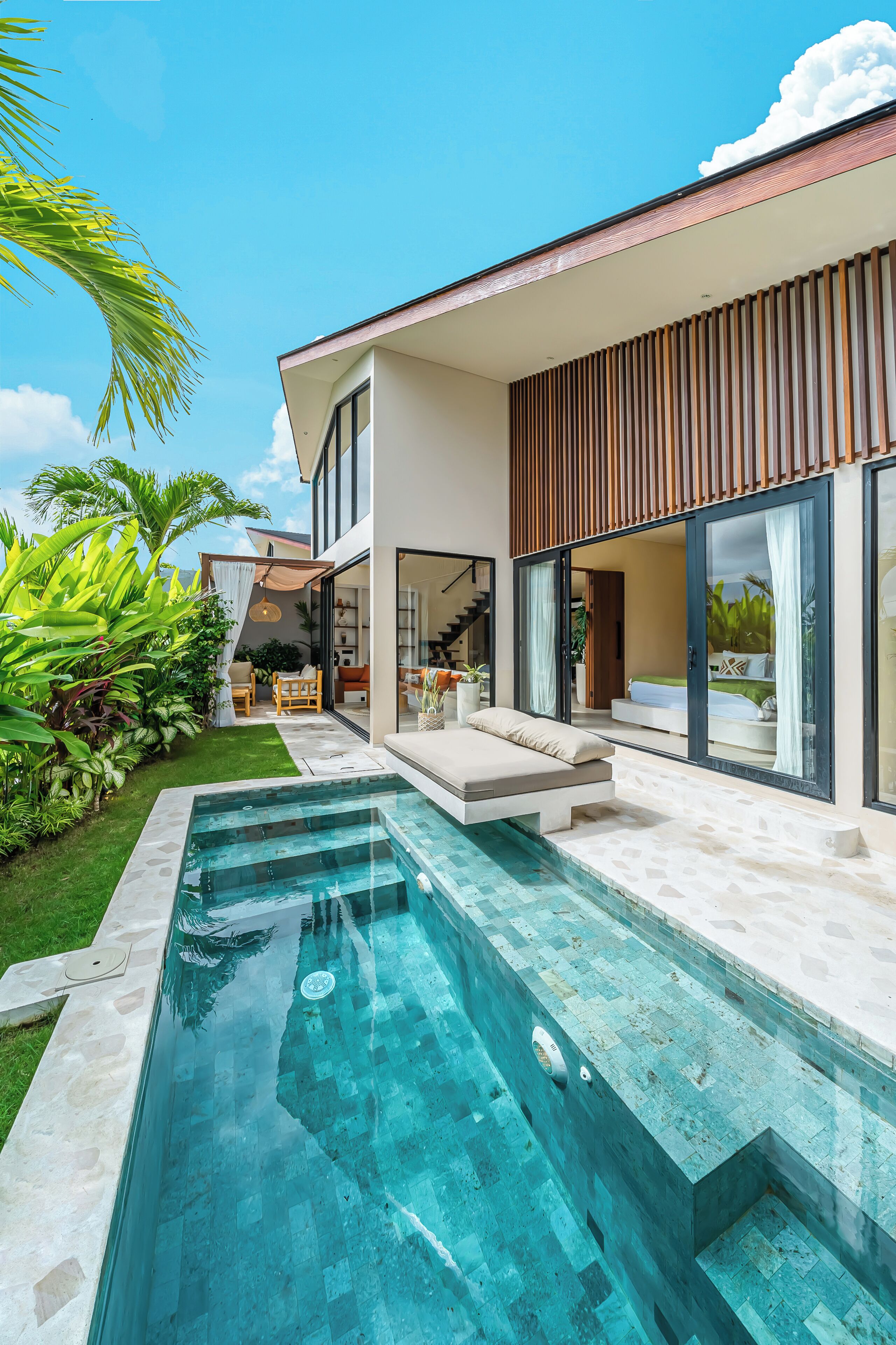 Ein modernes Haus mit Swimmingpool, Terrasse und einem großen Glasfenster, das in ein Schlafzimmer führt.