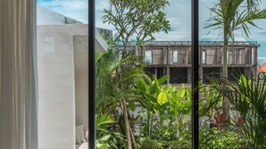Um banheiro moderno com uma banheira grande, vista para uma piscina e vegetação exuberante do lado de fora.