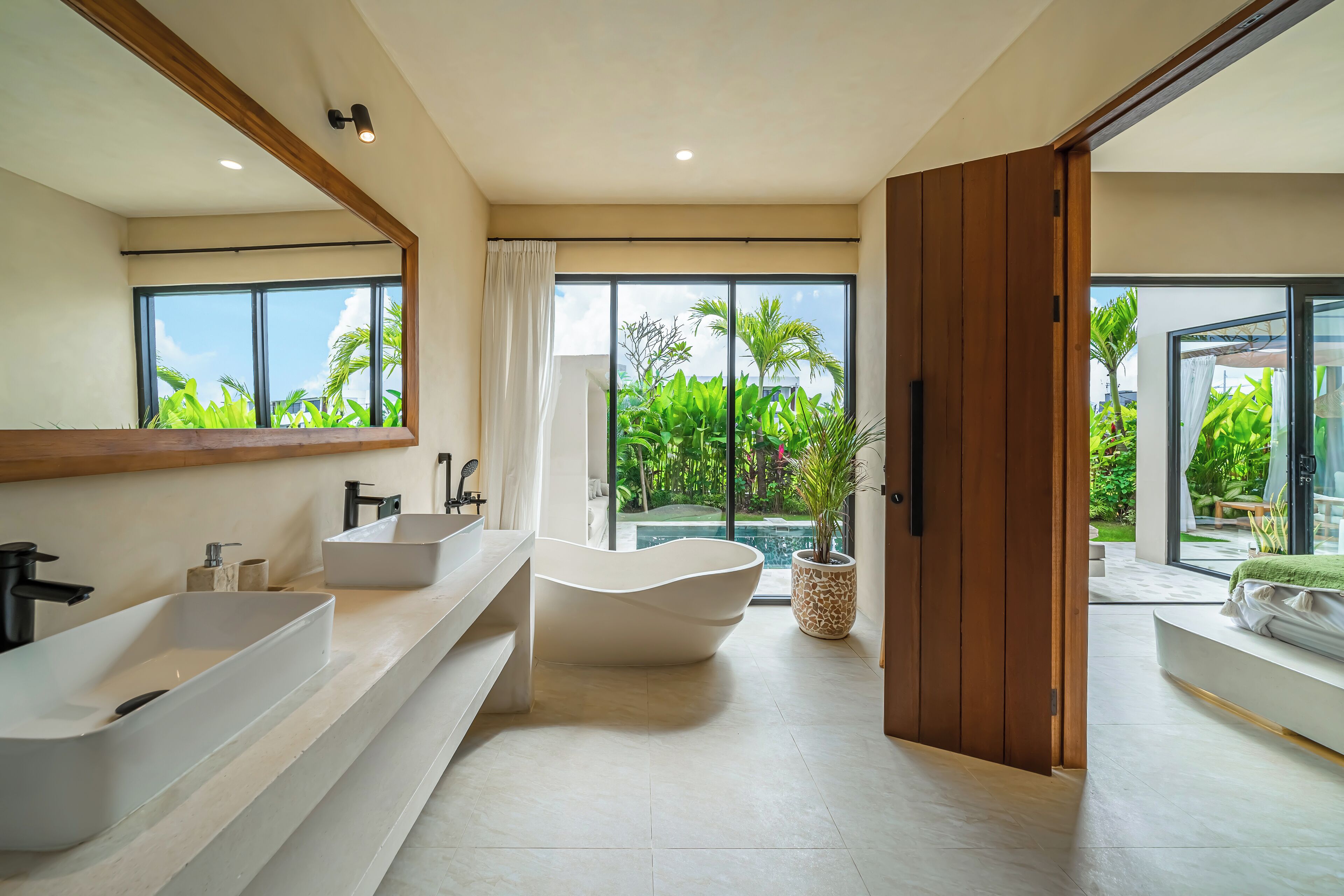 A modern bathroom with a freestanding bathtub, two sinks, and a large mirror.