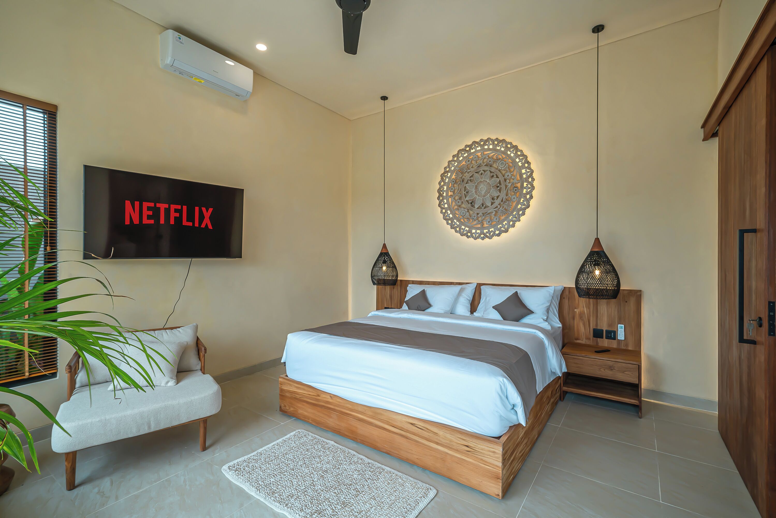 A modern bedroom with a large bed, a TV mounted on the wall, and a decorative wall piece.