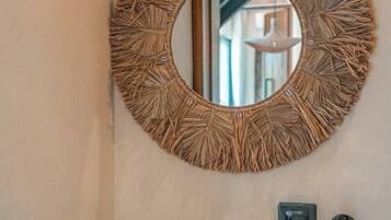 A bathroom with a round mirror with a natural leaf design, a teal sink, and a black faucet.