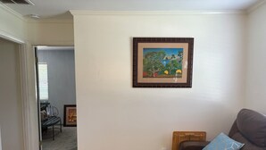 A living room with a brown leather sofa, a blue patterned pillow, a small wooden side table, and a framed painting of trees on the wall. - Charming Quiet 1-bedroom 1 bath ADU with AC, WiFi in Savannah (Savannah)