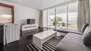 Un salon moderne avec un canapé, une table basse, un téléviseur et une grande fenêtre avec des rideaux.